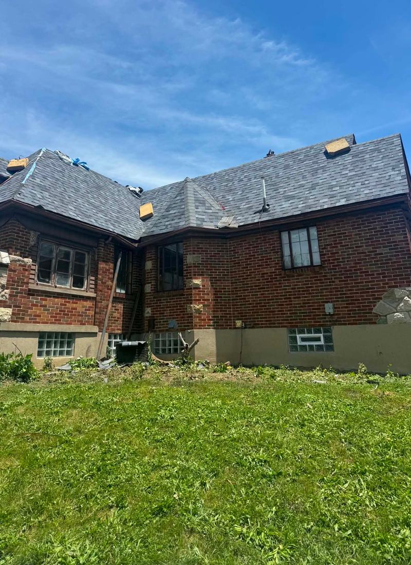 Crew working along the ridge of a brick two-story house